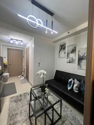 a living room with a black couch and a table at Modern apartment with balcony and Pool View in Manila
