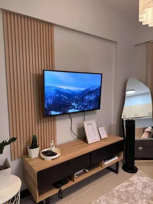 a living room with a flat screen tv on a wall at Alea Residences 2 Bedroom Condo with Pool View Balcony in Manila