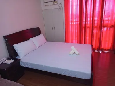 a bedroom with a bed with white sheets and red curtains at Grand Soho Makati in Manila