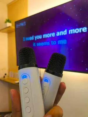a person holding two microphones in front of a tv at Azure Staycation in Manila