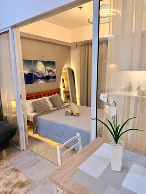 a bedroom with a bed and a table in a room at Azure Staycation in Manila