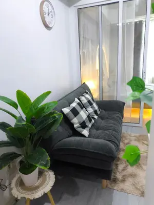 a black couch in a living room with a plant at Azure Staycation in Manila