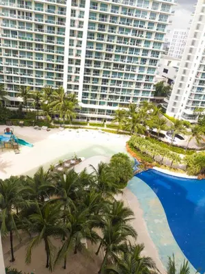 an aerial view of a resort with a pool and palm trees at Azure Staycation in Manila
