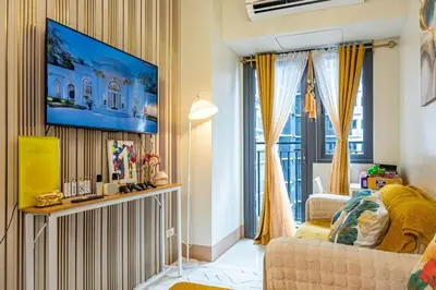 a living room with a couch and a tv on a wall at 1BR Near MOA Balcony & Wi-Fi in Manila