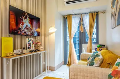 a living room with a couch and a tv on a wall at 1BR Near MOA Balcony & Wi-Fi in Manila