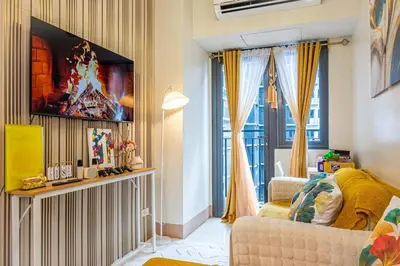 a living room with a couch and a tv on a wall at 1BR Near MOA Balcony & Wi-Fi in Manila