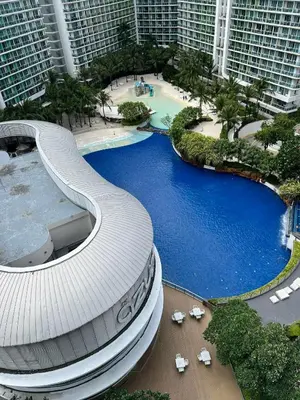 a curved building with a pool in front of tall buildings at The Bawhaus in Manila