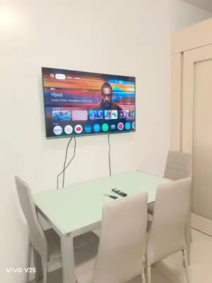 a white table with chairs and a tv on a wall at Sea Residences Joy in Manila