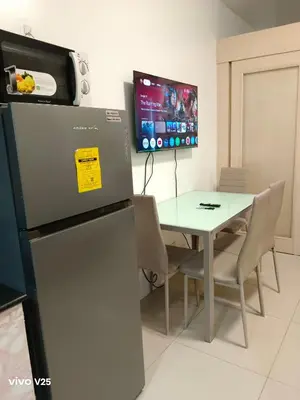 a dining room with a table and a refrigerator at Sea Residences Joy in Manila