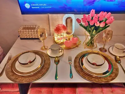a table with plates and a vase of pink flowers at Blush & Glam at SMDC Fame Residences Tower 3 in Manila