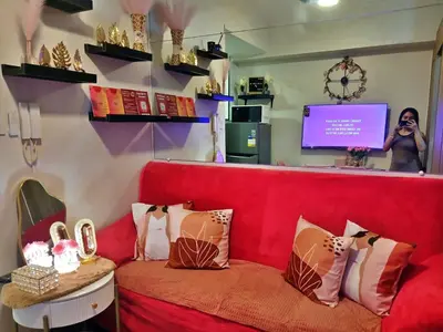a woman taking a picture of a red couch with pillows at Blush & Glam at SMDC Fame Residences Tower 3 in Manila