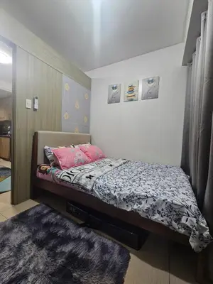 a small bedroom with a bed with pink pillows at Shore Residences Mall Of Asia Cj in Manila