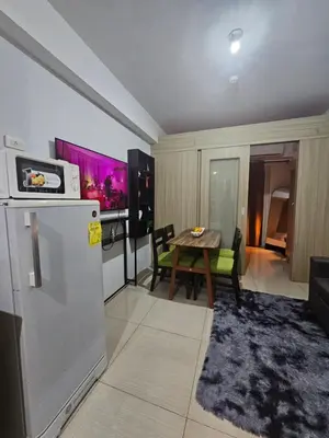 a kitchen with a refrigerator and a table in a room at Shore Residences Mall Of Asia Cj in Manila