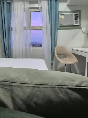 a bedroom with a bed and a window and a chair at 1128 Positano in Manila