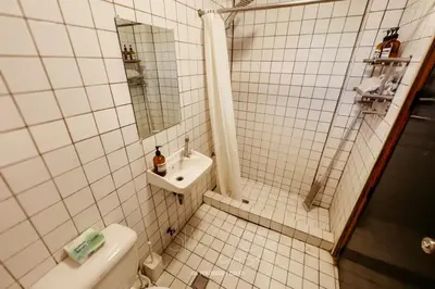 a white tiled bathroom with a toilet and a sink at Hidden Gem - Spacious Penthouse with Siargao Vibe in Manila