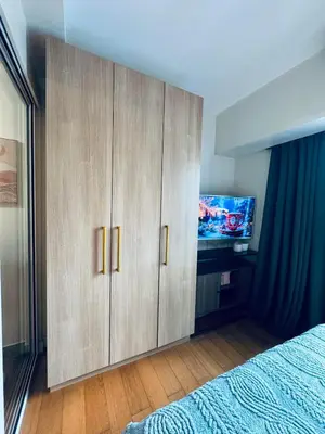 a bedroom with wooden cabinets and a tv in it at Pahinga Luxury Stays in Manila