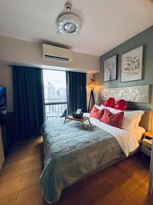 a bedroom with a large bed with red pillows at Pahinga Luxury Stays in Manila
