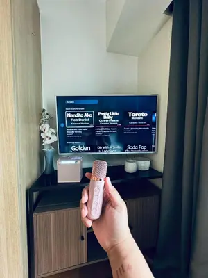 a person holding a remote control in front of a tv at Pahinga Luxury Stays in Manila