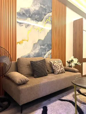 a couch in a living room with a painting on the wall at Shore Residences Direct Pool Access in Manila