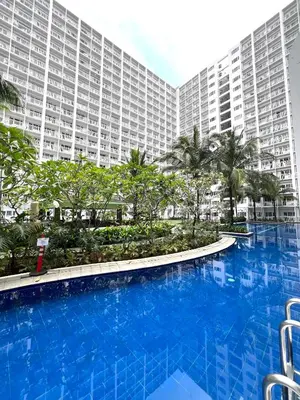 a large blue swimming pool in front of a large building at Shore Residences Direct Pool Access in Manila