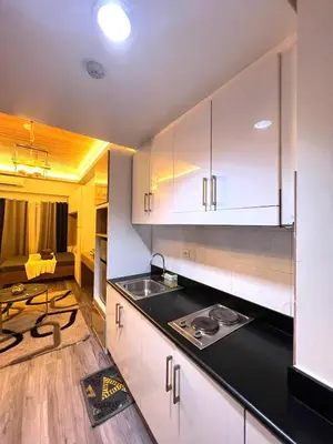 a kitchen with white cabinets and a black counter top at Shore Residences Direct Pool Access in Manila