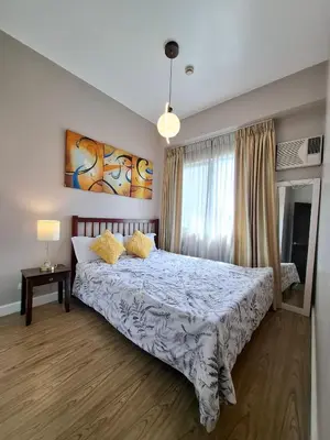 a bedroom with a large bed with yellow pillows at Cozy Hotel-Style 2 Bedroom Condo Unit at Eastbay Residences by Rockwell in Manila