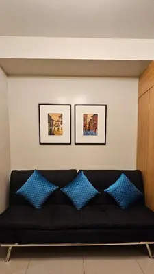 a black couch with blue pillows in a living room at Low Floor 1BR Balcony Shell near MOA Shell001 in Manila