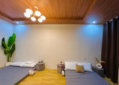 a living room with two beds and a chandelier at Tan's Homestay in Trece Martires