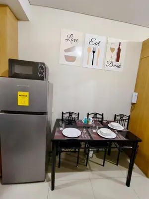 a dining room with a table and a refrigerator at MOA Condo Stay with balcony Pool View 2 Beds in Manila