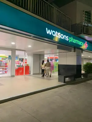 two people walking inside of a wisdom pharmacy store at MOA Condo Stay with balcony Pool View 2 Beds in Manila