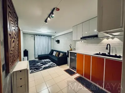 a kitchen and a living room with a couch in it at Malamaya Staycation in Manila
