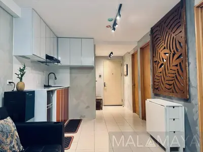 a kitchen with white cabinets and a black refrigerator at Malamaya Staycation in Manila