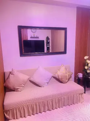a couch with pillows in a room with a mirror at Breeze Residences in Manila