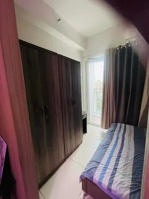 a bedroom with a bed and wooden cabinets and a window at Breeze Residences in Manila