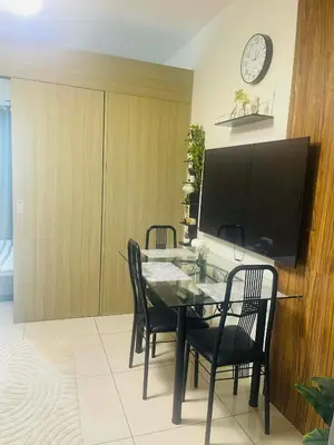 a dining room table with chairs and a clock on a wall at Breeze Residences in Manila