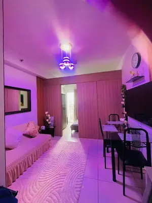 a purple room with a bed and a table at Breeze Residences in Manila