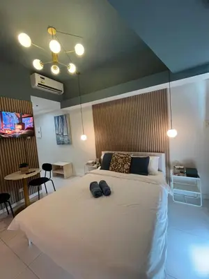 a bedroom with a large white bed with black shoes on it at Bleau Haven KL Service Residences Makati in Manila