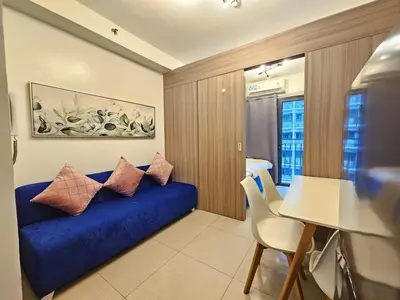 a living room with a blue couch with pillows on it at Shore 2 Tower 2 Pool View 1BR near MOA and NAIA Shore003 in Manila