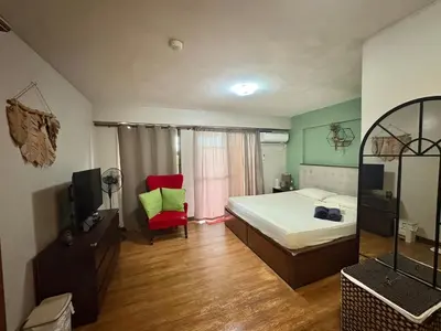 a bedroom with a bed and a red chair at Comfortable 1BR Pasig Apartment in Manila