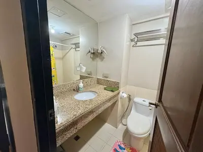 a bathroom with a sink and a toilet and a mirror at Comfortable 1BR Pasig Apartment in Manila
