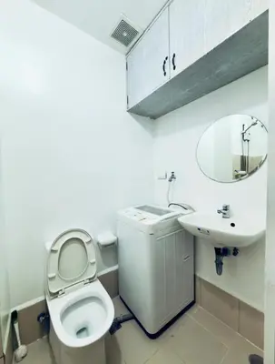 a white bathroom with a toilet and a sink at Netflix and Chill Ephra's Place in Manila
