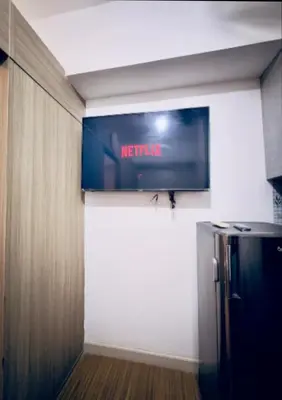 a television on the wall of a room with a refrigerator at Netflix and Chill Ephra's Place in Manila