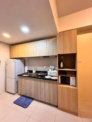 a kitchen with wooden cabinets and a white refrigerator at Staycation Casa Filipina in Manila