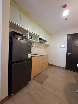 a kitchen with a black refrigerator and wooden cabinets at THE Faithful Nest in General Trias