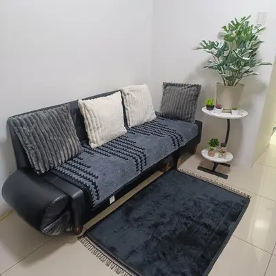 a black couch in a living room with a rug at Sea Residences StaycationAtMOA in Manila