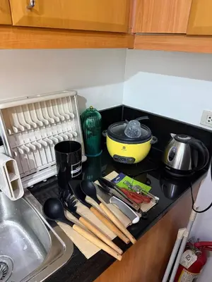a kitchen counter with a stove top with wooden utensils at The Luxe Forbeswood BGC in Manila