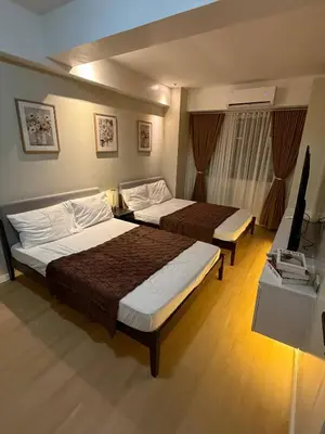 a hotel room with two beds and a television at The Luxe Forbeswood BGC in Manila