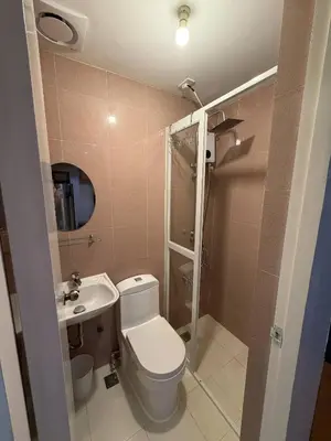 a bathroom with a toilet and a sink and a shower at The Luxe Forbeswood BGC in Manila