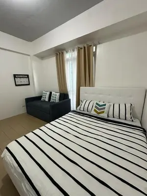a bedroom with a large bed and a couch at Sleep and Fly Condotel in Manila