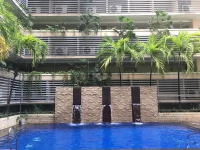 a swimming pool in front of a building with palm trees at Sleep and Fly Condotel in Manila